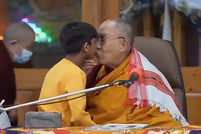in-a-video-that-has-sparked-controversy-throughout-the-world,-the-dalai-lama-kisses-a-young-indian-kid-and-instructs-him-to-“suck-my-tongue.”